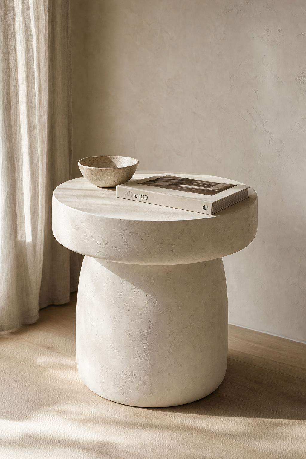 Sculptural micro-cement pedestal side table with hand-trowelled texture on a pale oak floor