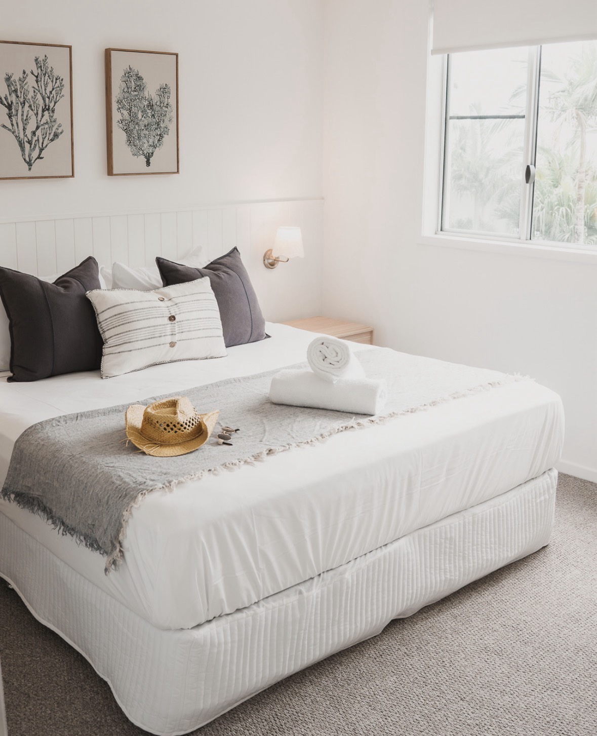 Nalani Airlie Beach master bedroom with white vertical VJ feature wall panelling, brass wall sconce and coastal styling